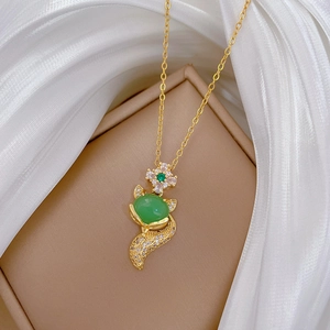 Detail of a luxury gold necklace featuring a green fox pendant with zircon diamonds