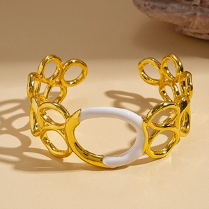 Détail d'un bracelet ouvert doré au design géométrique et incrustation d'émail blanc