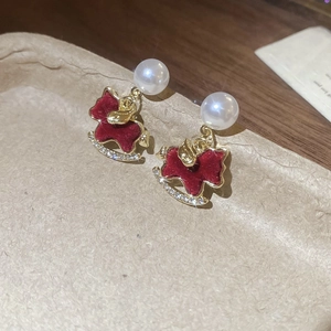 Macro shot of red flocked pony earrings with pearls and crystals on a rustic background