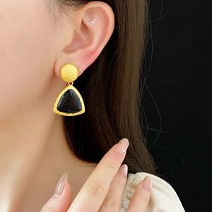 Close-up of model wearing gold triangle earrings with black enamel inlay in vintage style