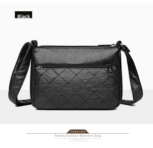 Detail of black faux leather crossbody bag with rhombic quilting and front zipper pocket