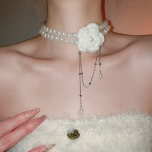 Gros plan du ras-du-cou en perles à double rang avec fleur tricotée et glands fins