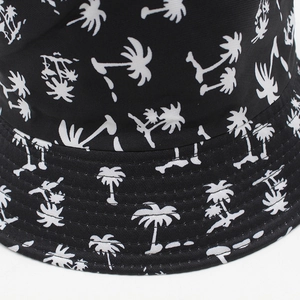 Reversible bucket hat with white palm tree print on black fabric, outdoor sun protection