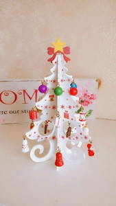 Close-up of white wooden DIY Christmas tree with colorful mini ornaments and golden star