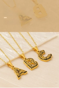 Detail of 18k gold plated letter necklace with vintage black textured pendant finish