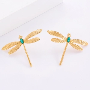 Gros plan de boucles d'oreilles libellule en métal doré avec incrustation de gemme verte