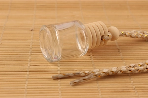 Close-up of 8ml glass car perfume bottle with wooden cap on bamboo mat
