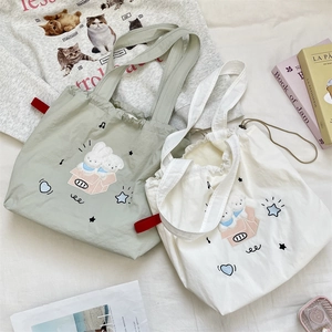 Piatto piano di borse tote con coulisse ricamate con motivo a coniglietto in verde e bianco