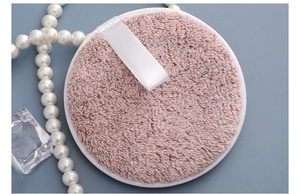 Close-up of pink round bamboo charcoal fiber makeup remover pad with white ribbon loop