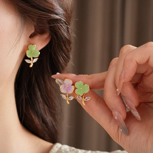 Detail view of gold-plated crystal flower earrings in green and purple colors