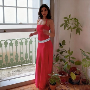 Detail of red satin maxi dress featuring a silver sequin waist belt and silky fabric drape