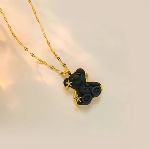 Detailed close-up of matte black bear pendant with golden star accents on a fine chain