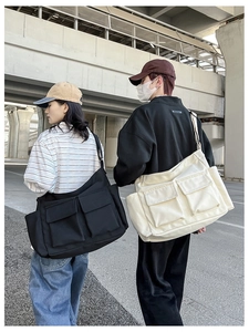 Outdoor shot of large canvas messenger bags in black and beige with dual pockets