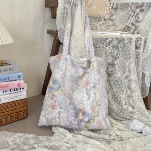 Detail of floral lace tote bag featuring intricate embroidery and branded woven label