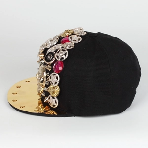 Detail of flat brim cap with gold mirror visor and metallic lion head punk studs