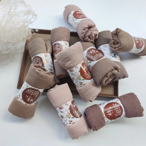 Detail of pleated cotton viscose scarves in Morandi tones with floral paper packaging