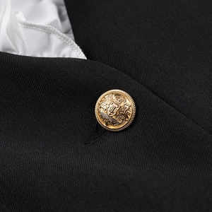 Detail of elegant black collar with white ruffled trim and a golden heraldic metal button