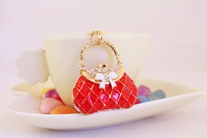 Macro detail of golden handbag keychain with red diamond lattice and white bow