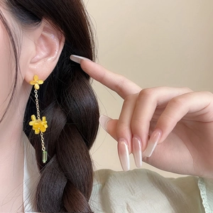 Detail view of floral dangle earrings with yellow flowers and long green glass beads