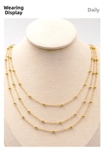 Close-up of triple-layered gold bead chain necklace on white jewelry bust display