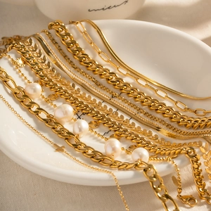 18K gold plated stainless steel cross anklets and necklaces with pearls on a white plate