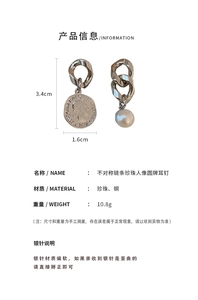 Detail view of asymmetric chain earrings with a vintage coin pendant and white pearl charm