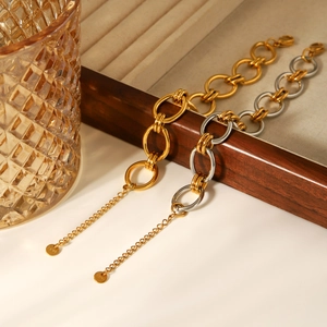 Détail du bracelet chaîne en acier inoxydable bicolore or et argent sur coffret en bois