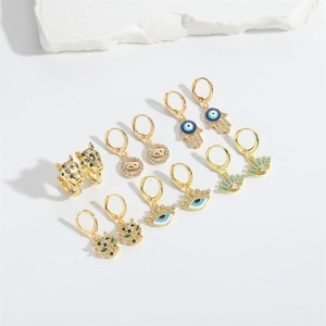 Goldene Creolen Set mit Bösem Blick, Hamsa Hand und Leoparden Design auf weißem Grund