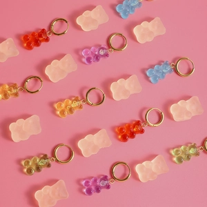 Boucles d'oreilles oursons en résine colorée avec anneaux dorés sur fond rose