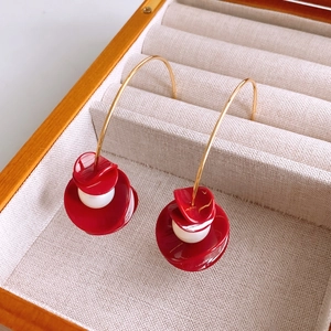 Detail of red petal resin drop earrings with white bead accents in a wooden jewelry box