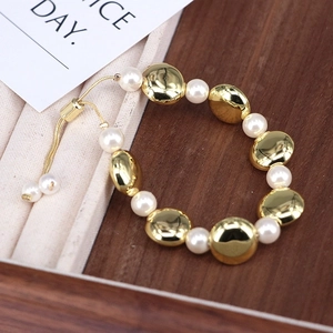 Adjustable gold beaded bracelet with white shell pearls on walnut wood and velvet tray