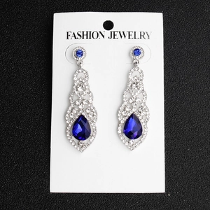 Macro shot of silver drop earrings with blue pear-shaped stones and clear rhinestones