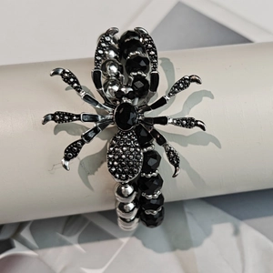 Detailed close-up of Gothic silver spider bracelet with black beads on a display