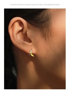 Detail of S925 silver banana stud earring with yellow enamel and micro zircons on ear