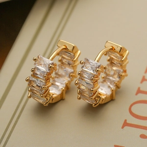 Close-up of gold huggie earrings with rectangular cubic zirconia in channel setting