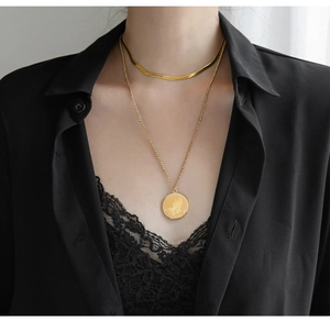 Detail of gold double-layer necklace set with flat snake chain and prayer hand coin pendant