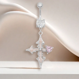 Détail macro d'un piercing de nombril argenté avec pendentif croix et gemme cœur rose