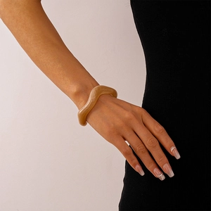 Close-up of wavy amber acrylic resin bangle on model with minimalist retro aesthetic