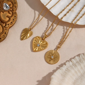 Dettaglio di collane placcate in oro 18K con ciondoli a cuore e foglia incisi e zirconi