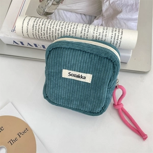 Detail of teal corduroy cosmetic pouch with soft texture and pink zip puller detail