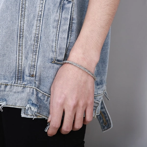 Close-up of a men's braided stainless steel wire cuff bracelet with wolf head detail