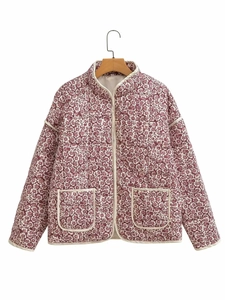 Close-up of quilted floral jacket with lavender print and cream piping on wood hanger