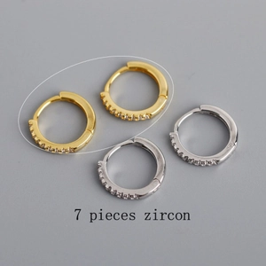 Détail de créoles en argent et or ornées de sept pierres de zircone cubique serties