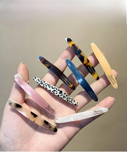 Detail of seven patterned acetate hair clips in tortoiseshell and pearl finishes
