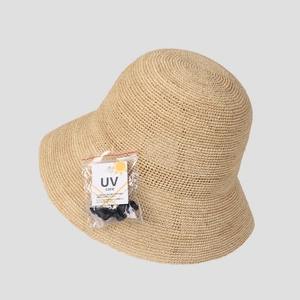 Detail of raffia straw sun hat with UV care tag and handmade woven texture