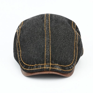 Detail of dark denim ivy cap with orange contrast stitching and brown faux leather brim