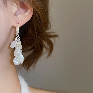 Gros plan de boucles d'oreilles pendantes argentées avec pétales nacrés sur un mannequin