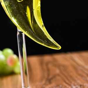 Close-up of a crescent-shaped glass cocktail horn with yellow liquid on a dark background