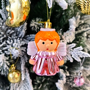 Vue détaillée d'un ange décoratif aux cheveux orange et robe rose sur un sapin de Noël