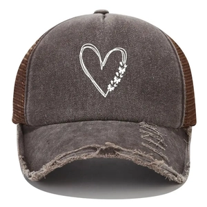 Detail of distressed brim and butterfly heart print on washed denim trucker hat